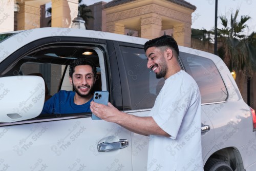 shot of two young Saudis chatting and having fun on the road, their features showing joy and happiness.