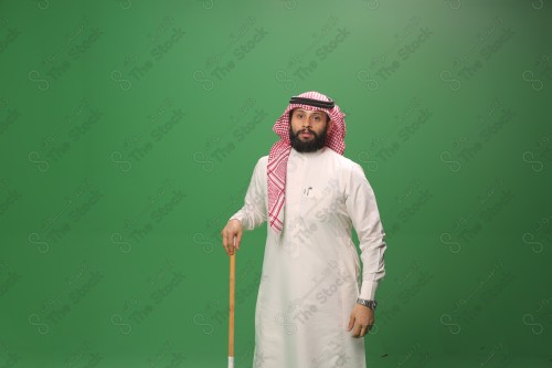 بورتريه رجل سعودي يرتدي الزي السعودي التقليدي يتكئ على العصا أثناء أداء رقصة المزمار الحجازية