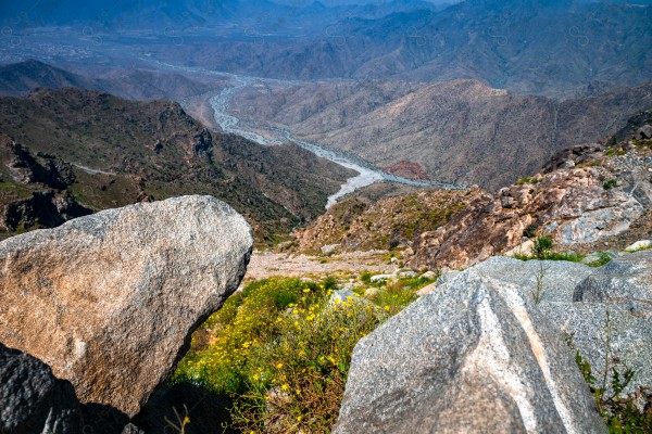 A snapshot of a series of towering rocky mountains and paved roads extending in the Al Hada Mountains in Taif, showing a cloudy sky during the day, mountain heights, Taif Mountains, mountain range