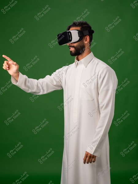A man wearing virtual reality glasses pointing with his hand on a green background.