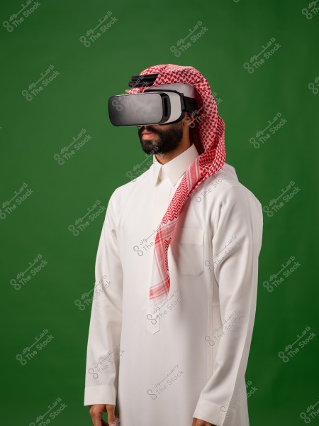 رجل يرتدي الثوب السعودي التقليدي مع نظارات الواقع الافتراضي وخلفية خضراء.