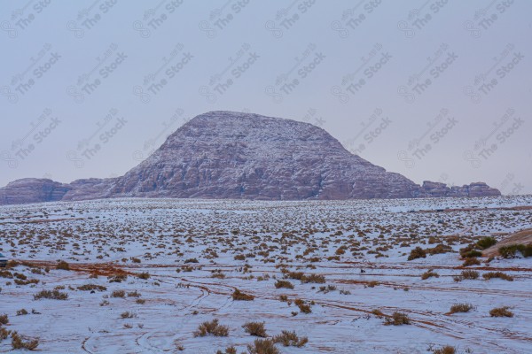 A snapshot of the snowy mountains in one of the regions in Saudi Arabia, and the sky appears to be semi-cloudy, in winter, a series of mountains covered with snow