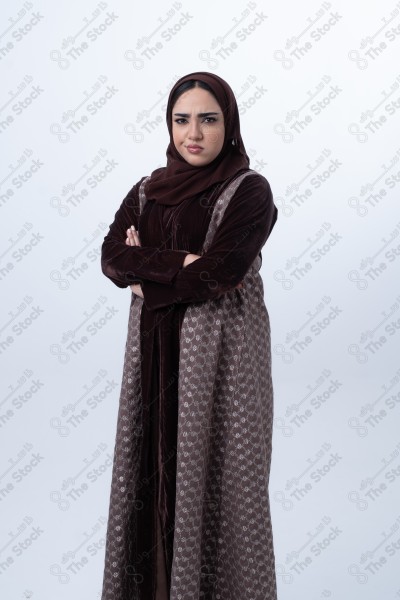 A young Saudi woman wearing an abaya and hijab, looking angry