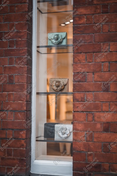 حقائب يد أنيقة معروضة في واجهة زجاجية على جدار من الطوب الأحمر.