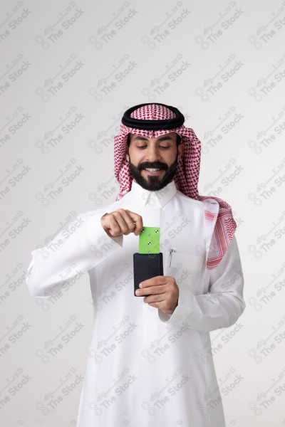 بورتريه رجل سعودي يحمل بطاقة خضراء على خلفية بيضاء