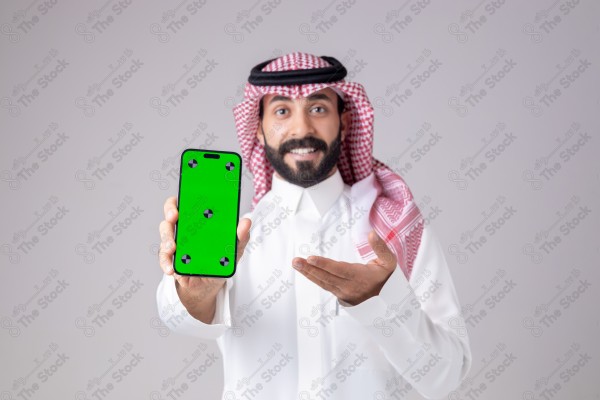 Portrait of a Saudi man holding a phone, pointing at the phone and making different expressions - green screen