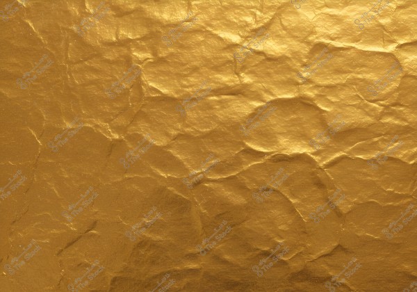 An image showing a gold-colored surface with a texture resembling crumpled paper. The surface features a uniform coloration with numerous creases that unevenly reflect light, giving it a rich and shiny appearance.