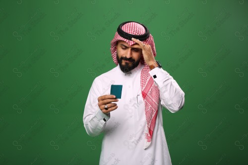 بورتريه رجل سعودي على خلفية خضراء محتار يحمل بطاقة الصرافة