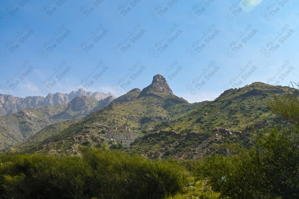 A snapshot of a series of towering rocky mountains and paved roads extending in the Al Hada Mountains in Taif, showing a cloudy sky during the day, mountain heights, Taif Mountains, mountain range