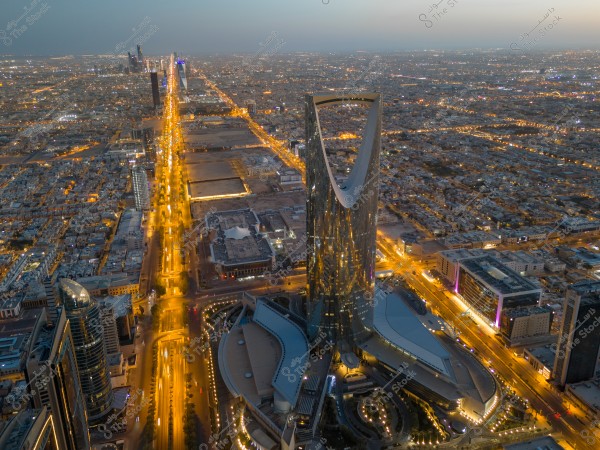 منظر جوي لأفق مدينة الرياض مع مبنى برج المملكة مضاءً في المساء.