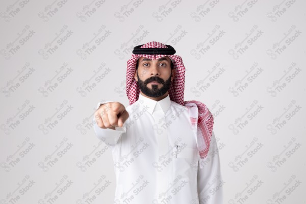 بورتريه رجل سعودي يقف على خلفية بيضاء ويشير بيده اتجاه معين