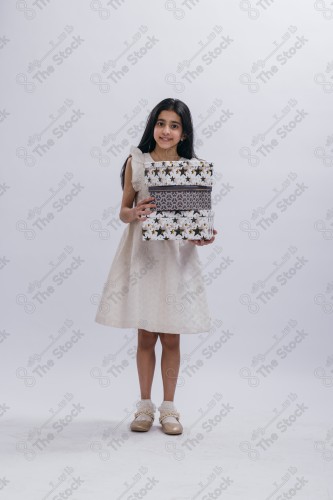 Portrait of a Saudi girl on a white background making gestures with her hands while smiling, souvenir photos, documenting a happy moment, Eid candy, Eid gifts, Eidiyat