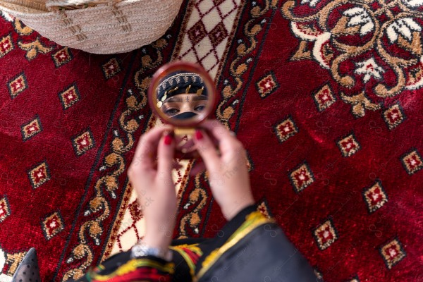 A shot of a Saudi woman whose eyes are reflected from the mirror wearing the traditional Saudi dress that represents the folklore, the day of foundation, the Saudi culture.