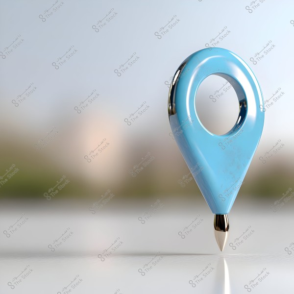 Image depicting a geographical location pin shape in light blue color, with a sharp tip at the bottom resembling a pen nib. The background is blurred with neutral colors, giving a sense of horizon or nature.