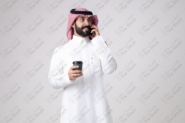 بورتريه رجل سعودي يحمل هاتف وكوب قهوة ويقوم بمكالمة هاتفية بتعابير مختلفة