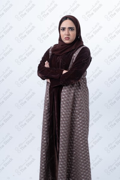 A young Saudi woman wearing an abaya and hijab, looking angry