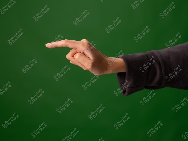 A hand pointing with the index finger on a green background.