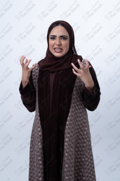 A young Saudi woman wearing an abaya and hijab, looking angry