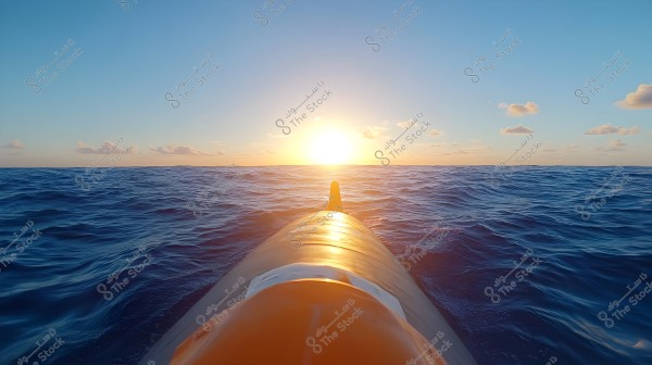 An image showing the front of a vessel floating on the ocean\'s surface with the sunset in the background. The sky is clear with a few light clouds, creating a rich color palette with gradients of blue, orange, and yellow.