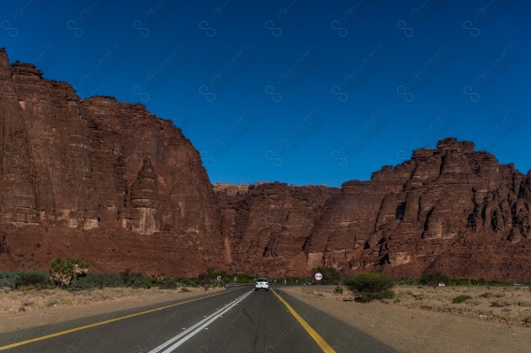 لقطة جوية لسلسلة من الجبال الصخرية في وادي بتبوك بالسعودية وتبدوا السماء صافية نهارًا،مجموعة من الأشجار في أحد الأودية في تبوك ، حياة برية .