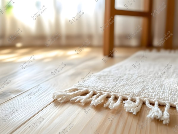 An image depicting part of a living room with minimalist decor. In the foreground, a soft white rug with tassels is seen on a light-colored wooden floor. In the background, a wooden chair is partially visible, and gentle sunlight filters through sheer curtains, giving a warm and tranquil ambiance.