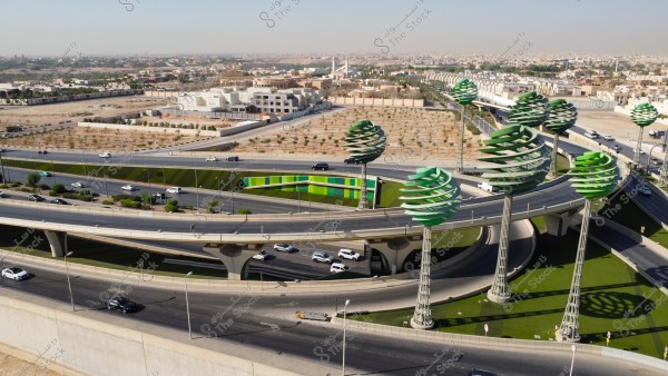 تصوير جوي لحركة سير السيارات على الطريق السريع في مدينة الرياض، الفن الهندسي المعماري للمجسمات الفنية على شكل أشجار خضراء، الطرق المتقاطعة في دوار عرقة بالمملكة العربية السعودية، البنية التحتية المتطورة