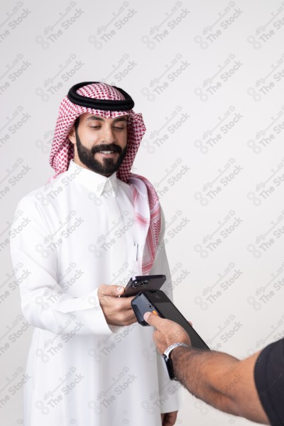 Portrait of a Saudi man holding a card and making automatic payments on a white background