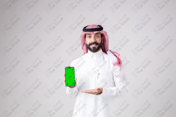 Portrait of a Saudi man holding a phone, pointing at the phone and making different expressions - green screen