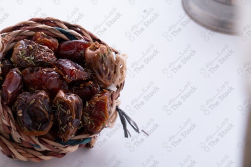 Close-up to a group of dates in a traditional bowl on a white background, a bowl of hoarded dates.