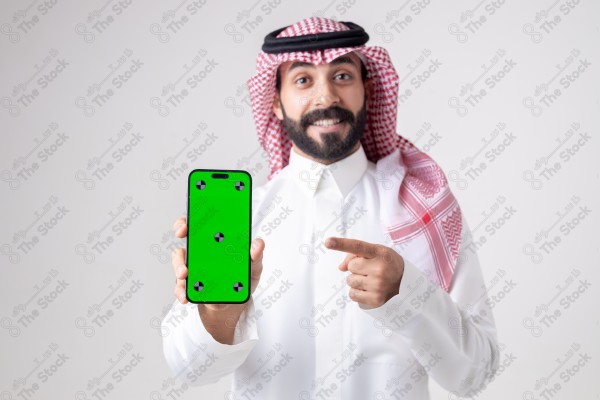 Portrait of a Saudi man holding a phone, pointing at the phone and making different expressions - green screen