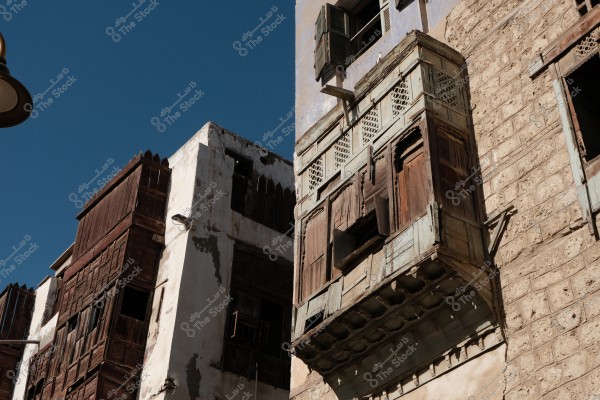 Old traditional buildings in Jeddah showing architectural details and wooden windows under a blue sky.