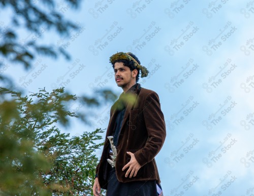 A Saudi man wearing a traditional dress at the top of the mountain and behind him clouds appear in Jizan