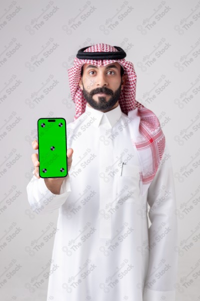 Portrait of a Saudi man holding a phone, pointing at the phone and making different expressions - green screen