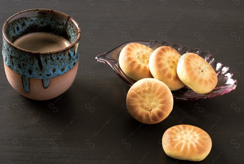 Close-up  a cup of hot black coffee and a plate of maamoul on a wooden table. Snack.