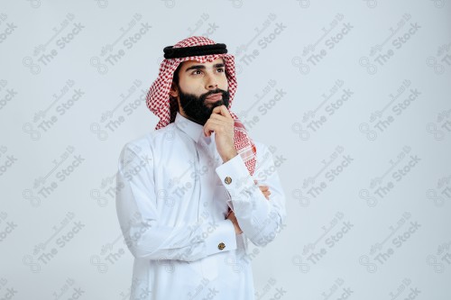 بورتريه رجل سعودي يرتدي الزي الرسمي التقليدي على خلفية بيضاء يقوم بعمل اشارات بيديه وهو مبتسم ، صور تذكارية ، توثيق لحظة سعيدة.