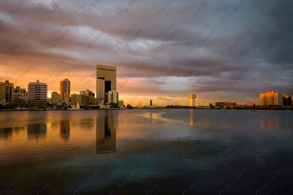 A shot of a group of buildings and landmarks at sunset showing a cloudy sky, buildings and landmarks, rivers and seas.