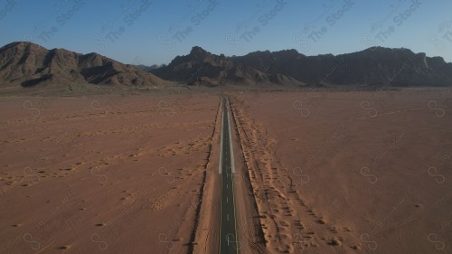 A chain of mountains on a road between sand dunes in the Empty Quarter desert.