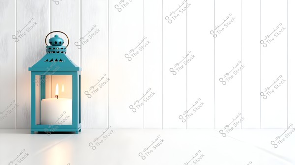 A blue lantern with a lit candle inside placed on a white floor against a white wooden wall. The lantern has a simple design with a round handle on top.