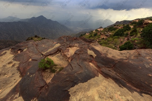 Aerial shot of a series of rocky mountains and the overlapping of clouds between them, nature in Saudi Arabia, the sky is clear