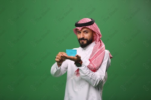 رجل سعودي على خلفية خضراء مبتسم يحمل بطاقة الصراف جاهز للتسوق