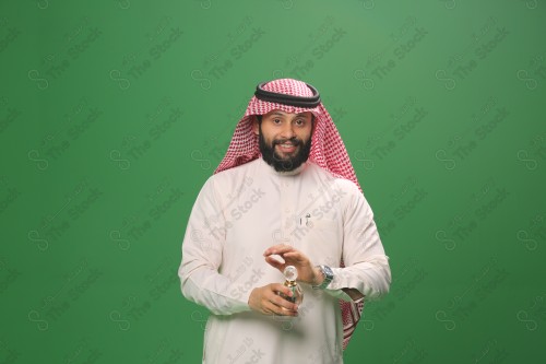 بورتريه رجل سعودي يرتدي الزي السعودي التقليدي يحمل زجاجة دهن عود