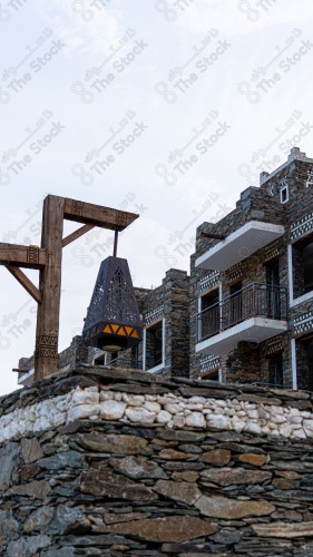 An ancient building built of stones in the middle of a group of windows surrounded by white paint while the sky looks cloudy during sunset, Rijal Almaa Heritage Village in the Asir region