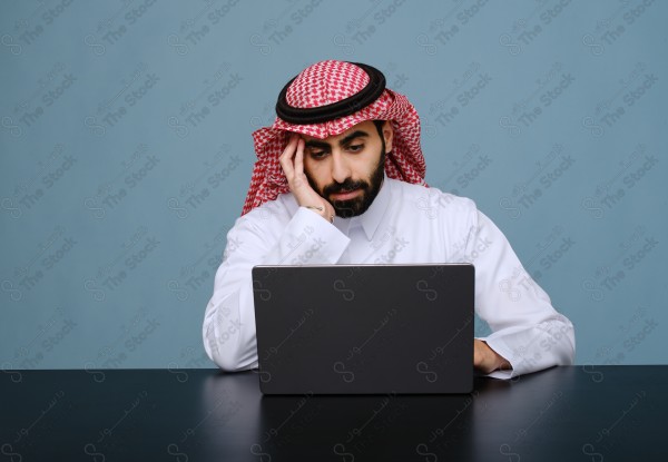 بورتريه شاب سعودي يرتدي الزي السعودي يستخدم جهاز المحمول ويتفاعل معه ، يقف على خلفية سماوية.