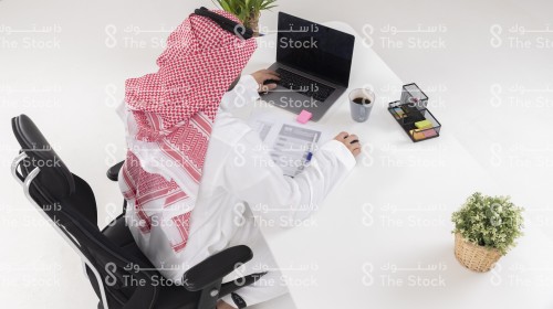 موظف سعودي يرتدي الزي السعودي التقليدي يعمل في المكتب