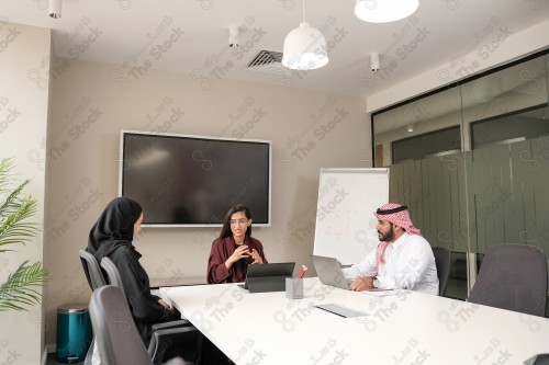 A Saudi woman wearing an abaya runs a business meeting in the boardroom during the day