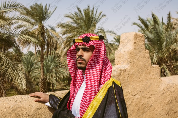 A snapshot of a Saudi man wearing folkloric costume on the day of the foundation stands over a mud building, heritage uniform, on the day of establishment, old archaeological buildings.