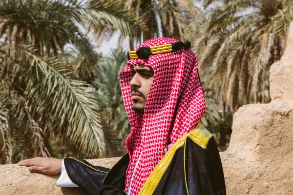 A snapshot of a Saudi man wearing folkloric costume on the day of the foundation stands over a mud building, heritage uniform, on the day of establishment, old archaeological buildings.