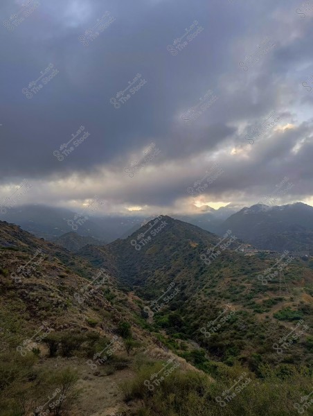 منظر طبيعي لجبال خضراء تحت غيوم كثيفة في السماء.