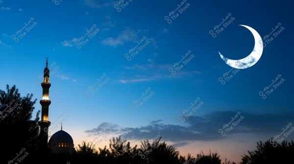 The image shows a view of a mosque\'s minaret beautifully lit at sunset, with a bright white crescent moon in the dark blue sky. Trees are silhouetted in black in the foreground.