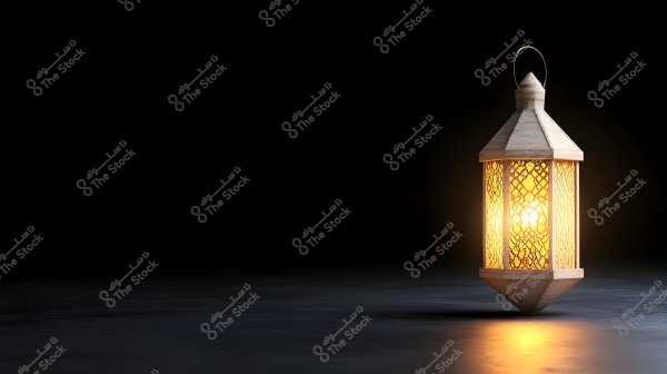 A wooden lantern illuminated in the dark with geometric designs on the glass, glowing with a warm yellow light. It is placed on a partially reflective surface, projecting soft shadows of the lantern. The background is completely black, accentuating the lantern\'s glow.